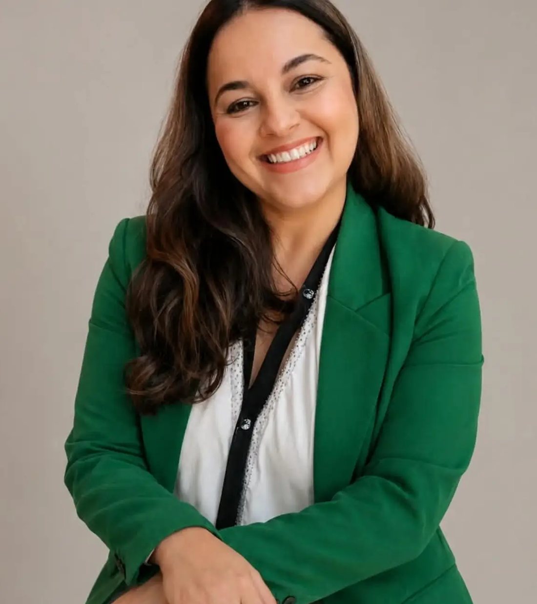 Dra. Ana Cristina sorrindo, de blazer verde, sentada em estúdio