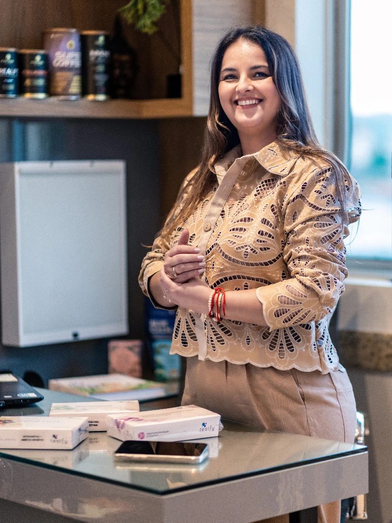 Dra. Ana Cristina em pé no consultório, ao lado da mesa